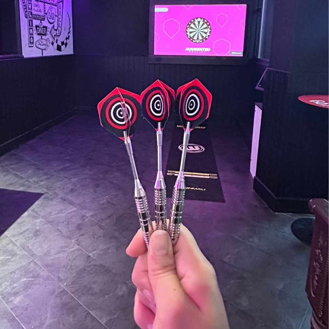Three darts held up in front of the darts lane at Bugsy’s